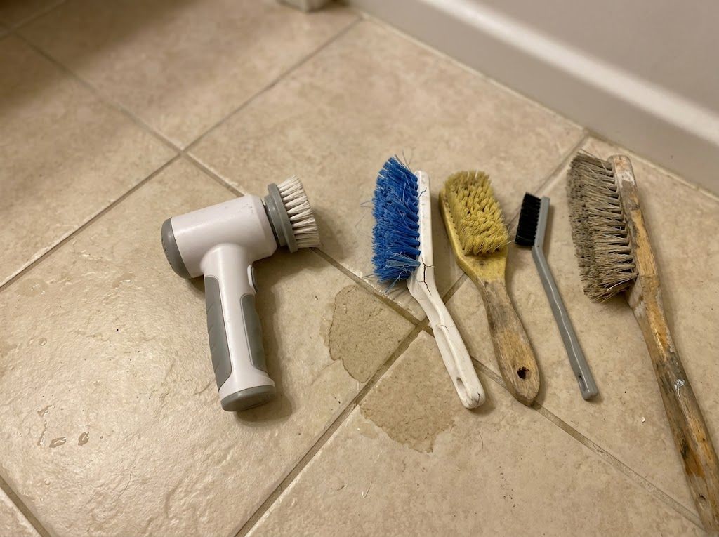 An electric scrubbing tool resting on a kitchen counter beside a sponge