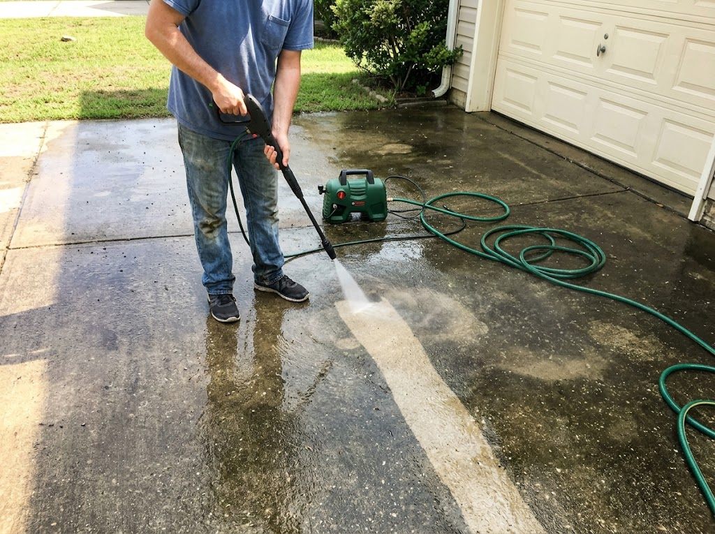 A pressure washer in mid-spray cleaning a concrete patio